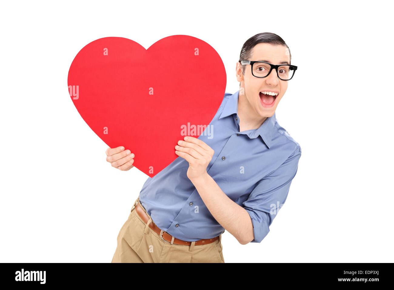 Joyful young man holding a big red heart isolated on white background ...
