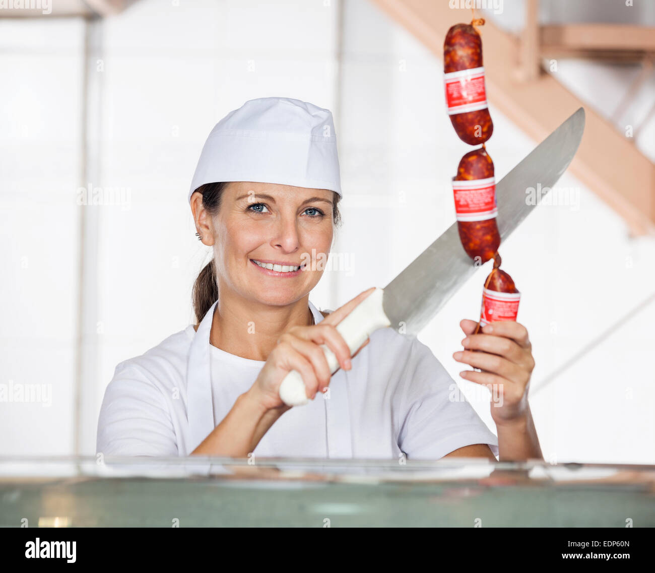 Female Butcher Cutting Sausages At Counter Stock Photo Alamy