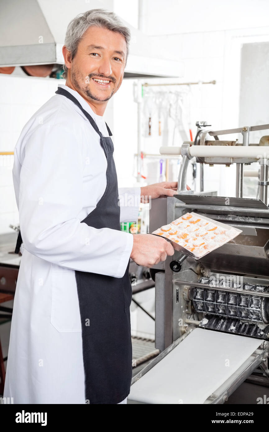 Happy Chef Using Ravioli Pasta Machine At Kitchen Stock Photo
