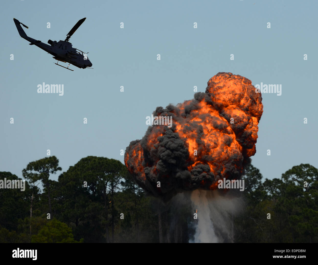 Military helicopter flying over fiery explosion and fireball Stock Photo