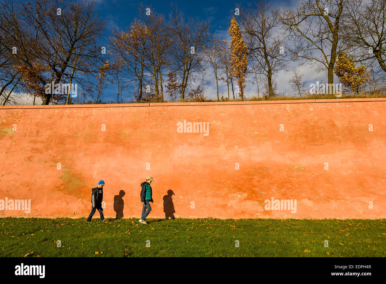 two boys walking along high wall in autumn Stock Photo