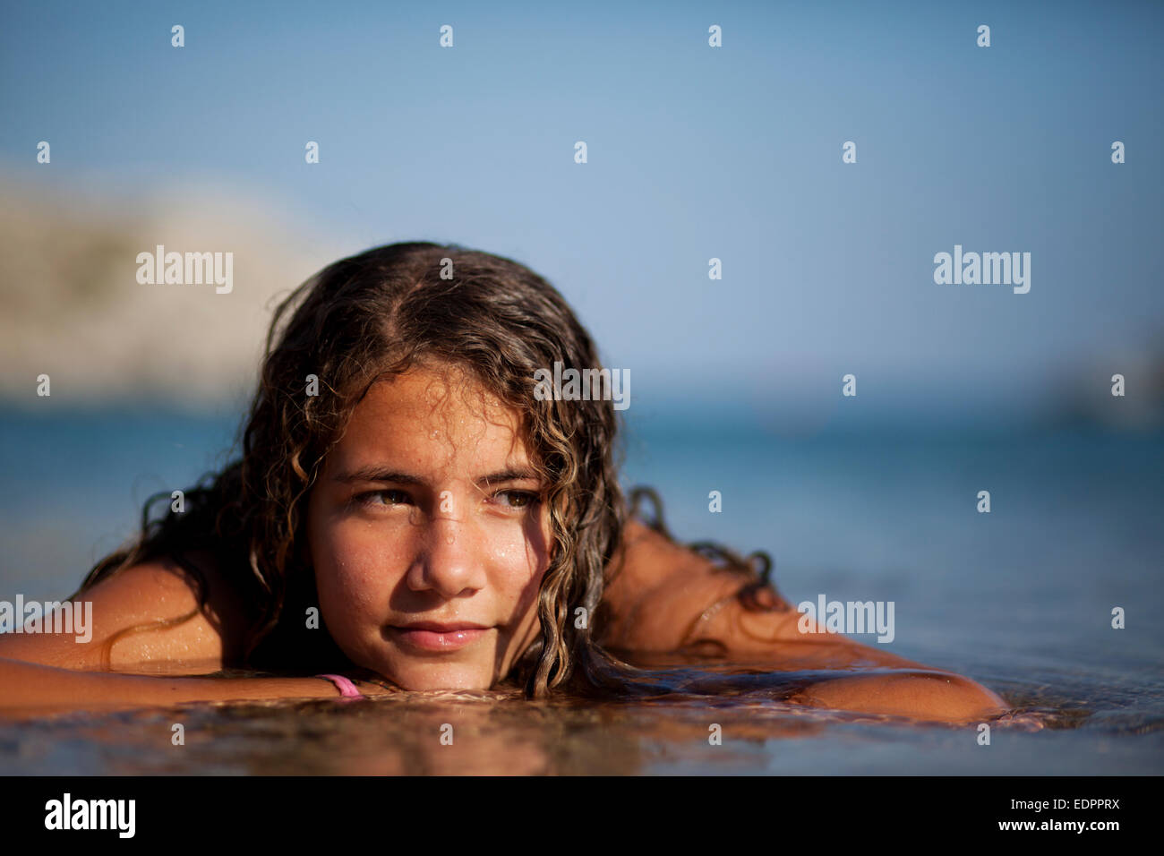 Beautiful teenager girl at the shore daydreaming in the water Stock Photo