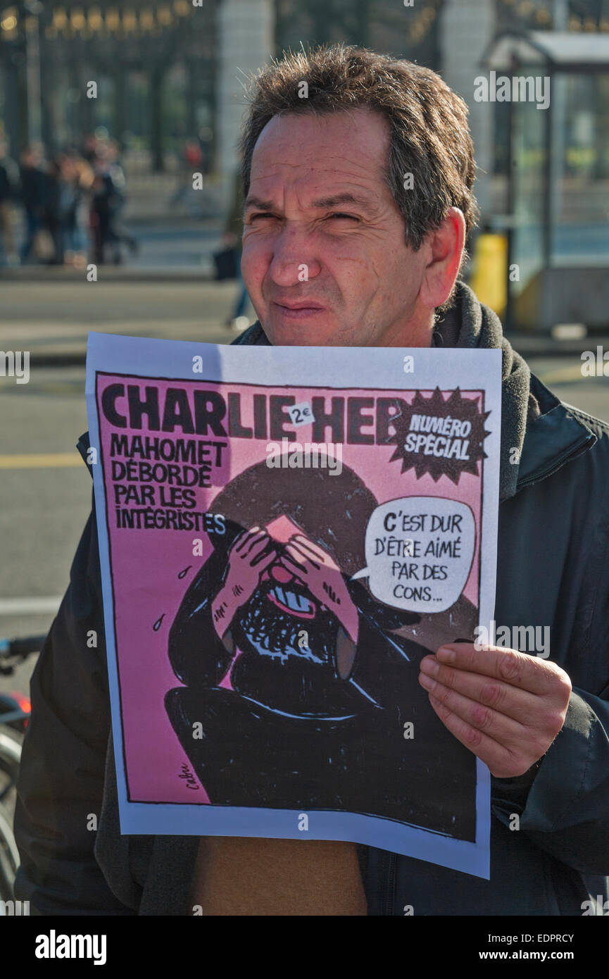 Geneva, Switzerland. 8th January 2015. A Swiss journalist holds up a cover of a past issue of Charlie Hebdo during a vigil by writers and members of International PEN in Geneva's Place de Neuve to show solidarity with the victims of the attack against the magazine. Credit:  Alistair Scott/Alamy Live News Stock Photo
