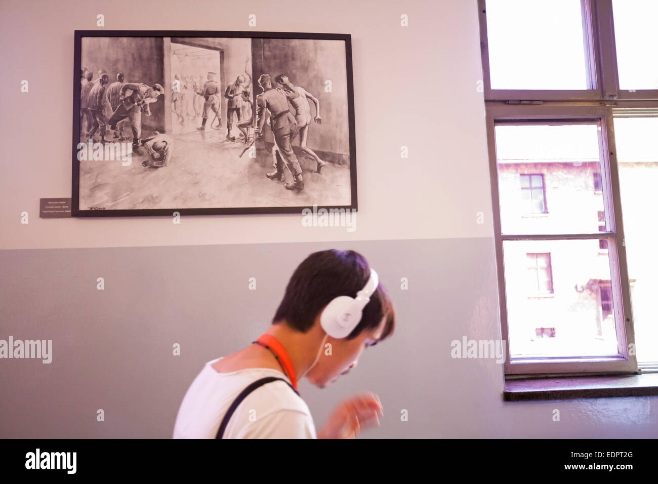 Visitor hurrying past picture on wall of Beginning of torment baths inside the Auschwitz concentration camp, Auschwitz, Poland Stock Photo