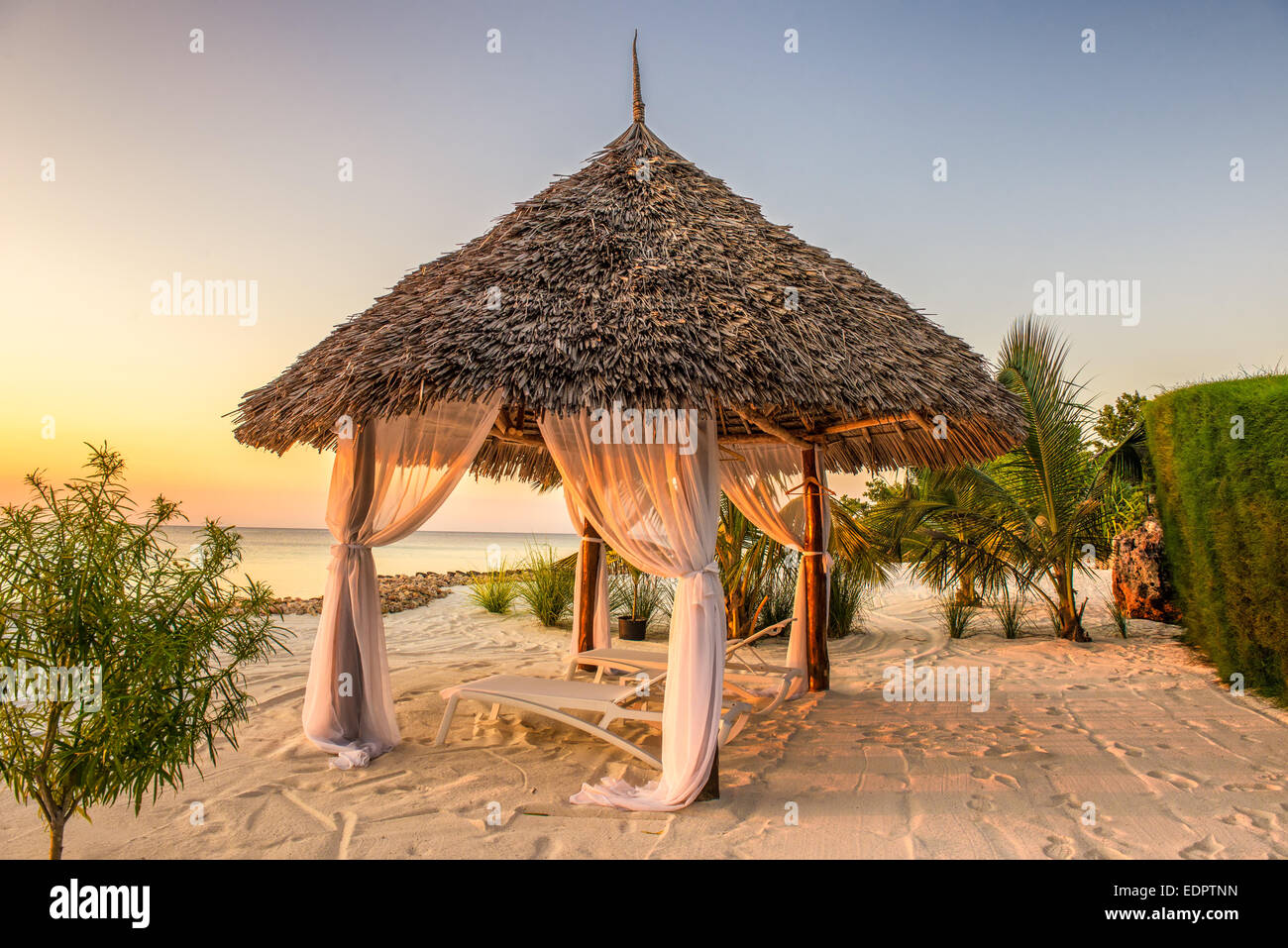 Beach lounge chairs at sunset at the shore of Indian ocean, Zanzibar, Tanzania Stock Photo