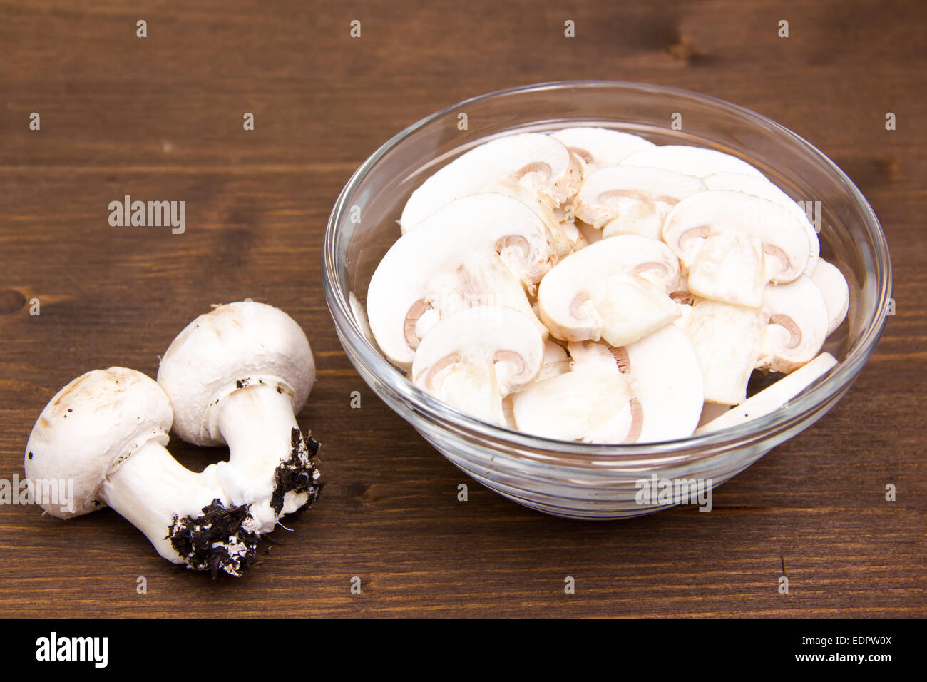Sliced mushrooms in bowl on wooden table Stock Photo