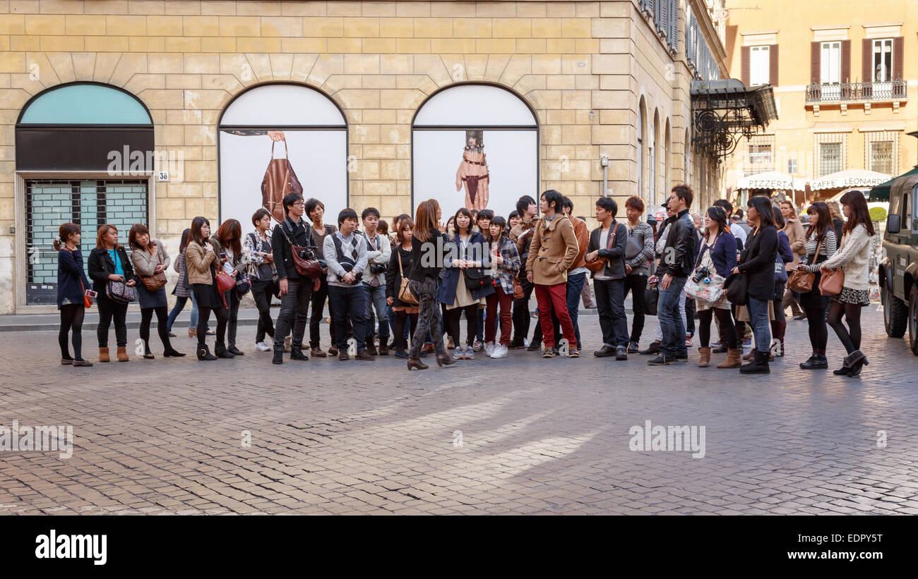 Asian tourist group gathering around their guide in the streets of Rome, Italy. Stock Photo