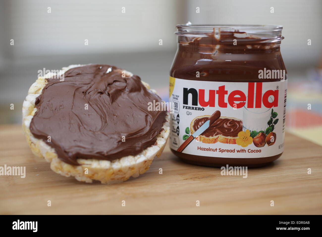 A butter flavored rice cake with Nutella spread on a wooden cutting