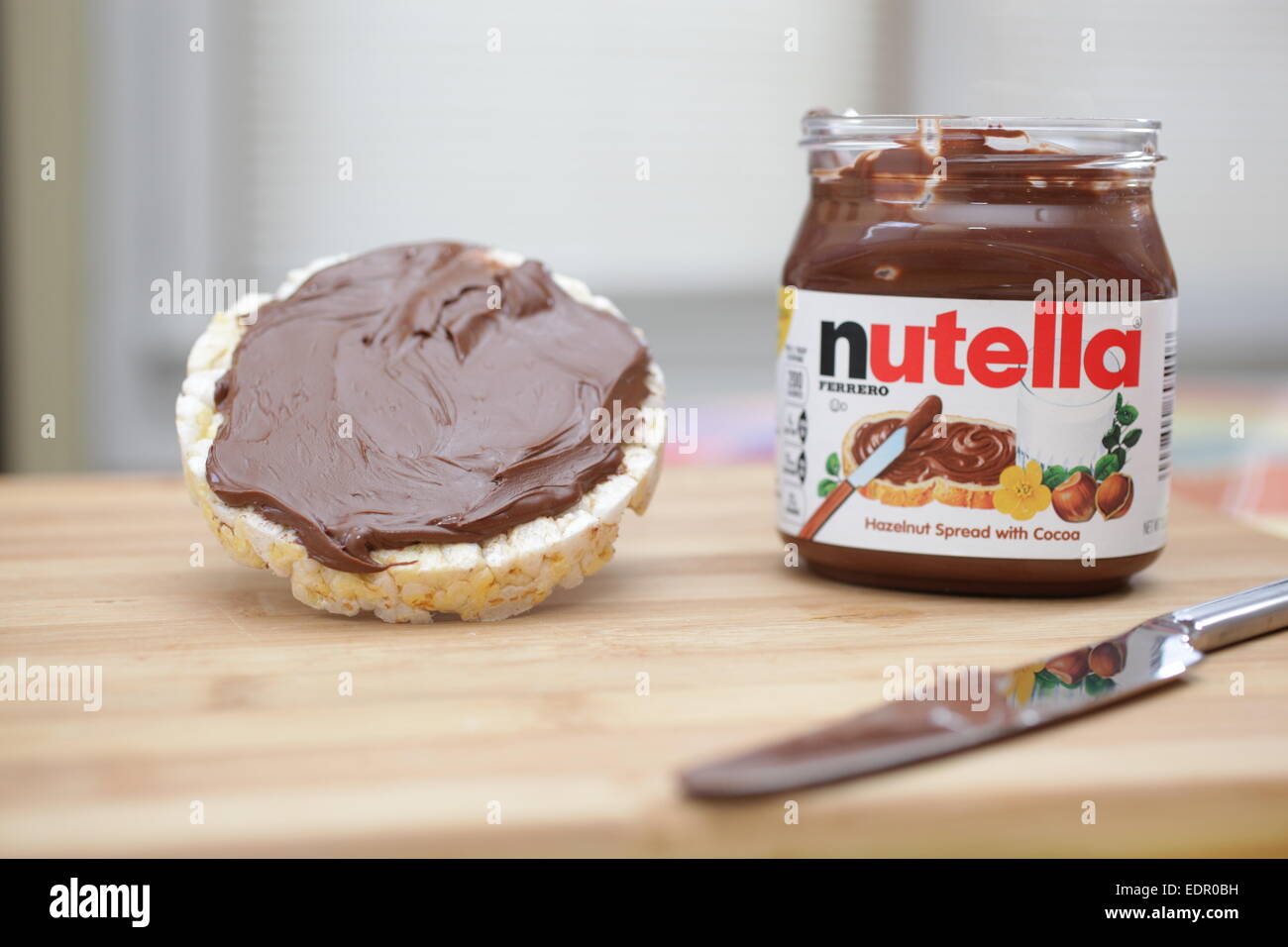 A butter flavored rice cake with Nutella spread on a wooden cutting
