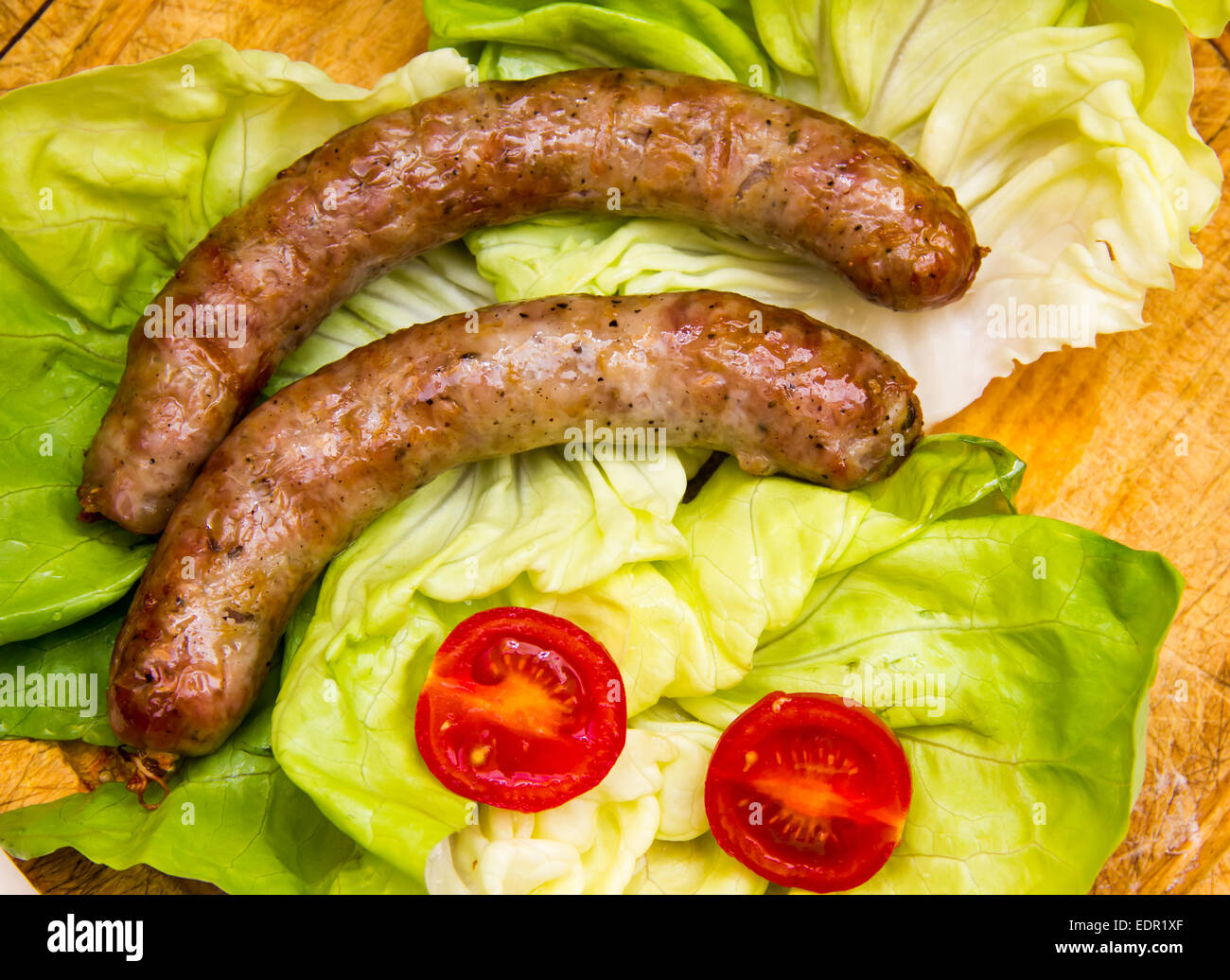 Sausage on wooden cutting board with salad top view Stock Photo
