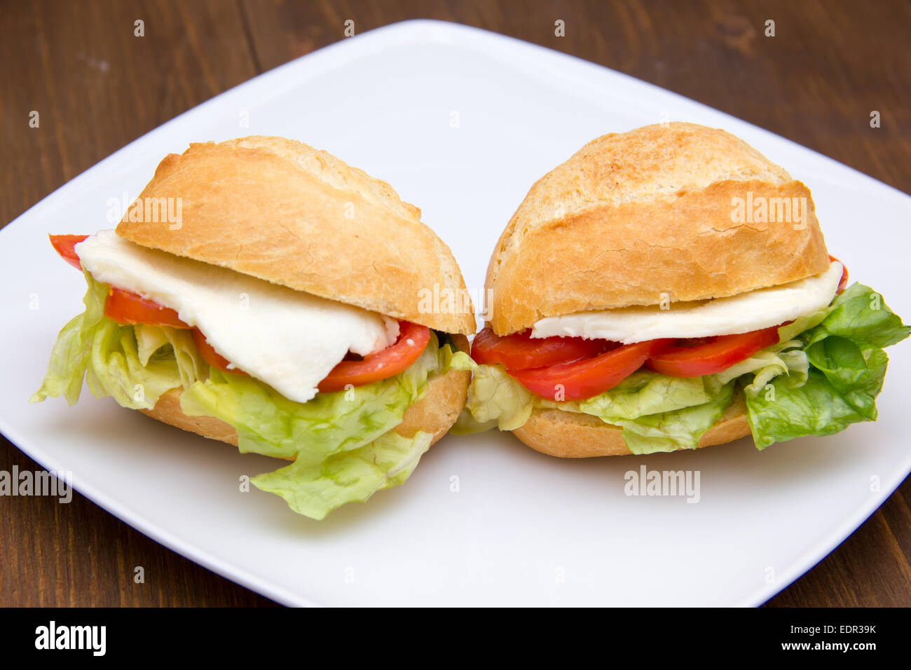 Sandwiches with tomato and cheese on plate over wooden table seen up close Stock Photo
