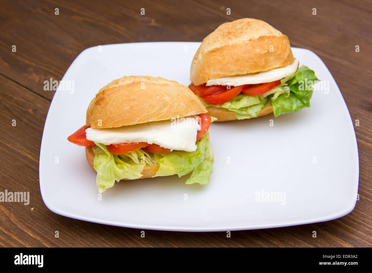 Sandwiches with tomato and cheese on plate over wooden table Stock Photo