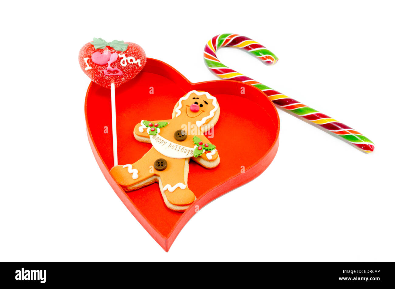 Gingerbread a candy cane and a lollipop in a heart shaped box isolated on white background Stock Photo