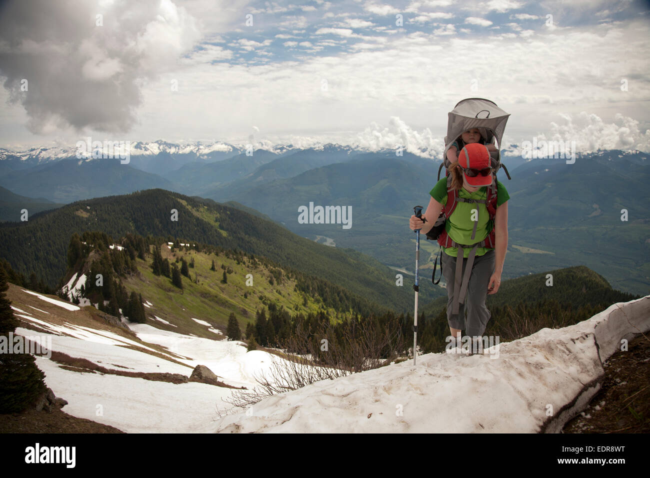 A woman carrying an infant hiking in the mountains. hiking in the mountains. Stock Photo