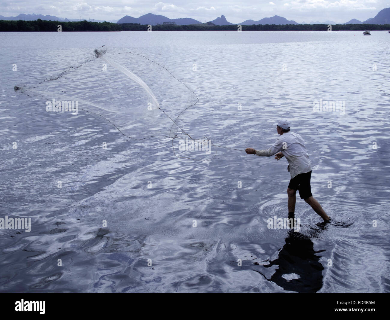 Man throwing and pulling in fishing net in river, Vitoria, Espirito Santo, Brazil. Stock Photo
