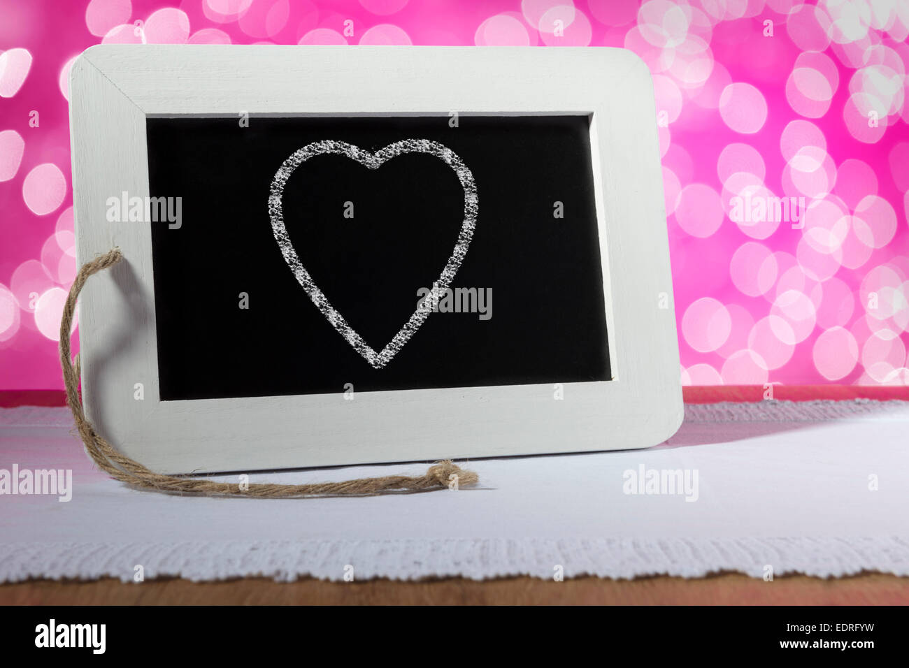 Image of a slate blackboard with chalk heart on pink background Stock Photo
