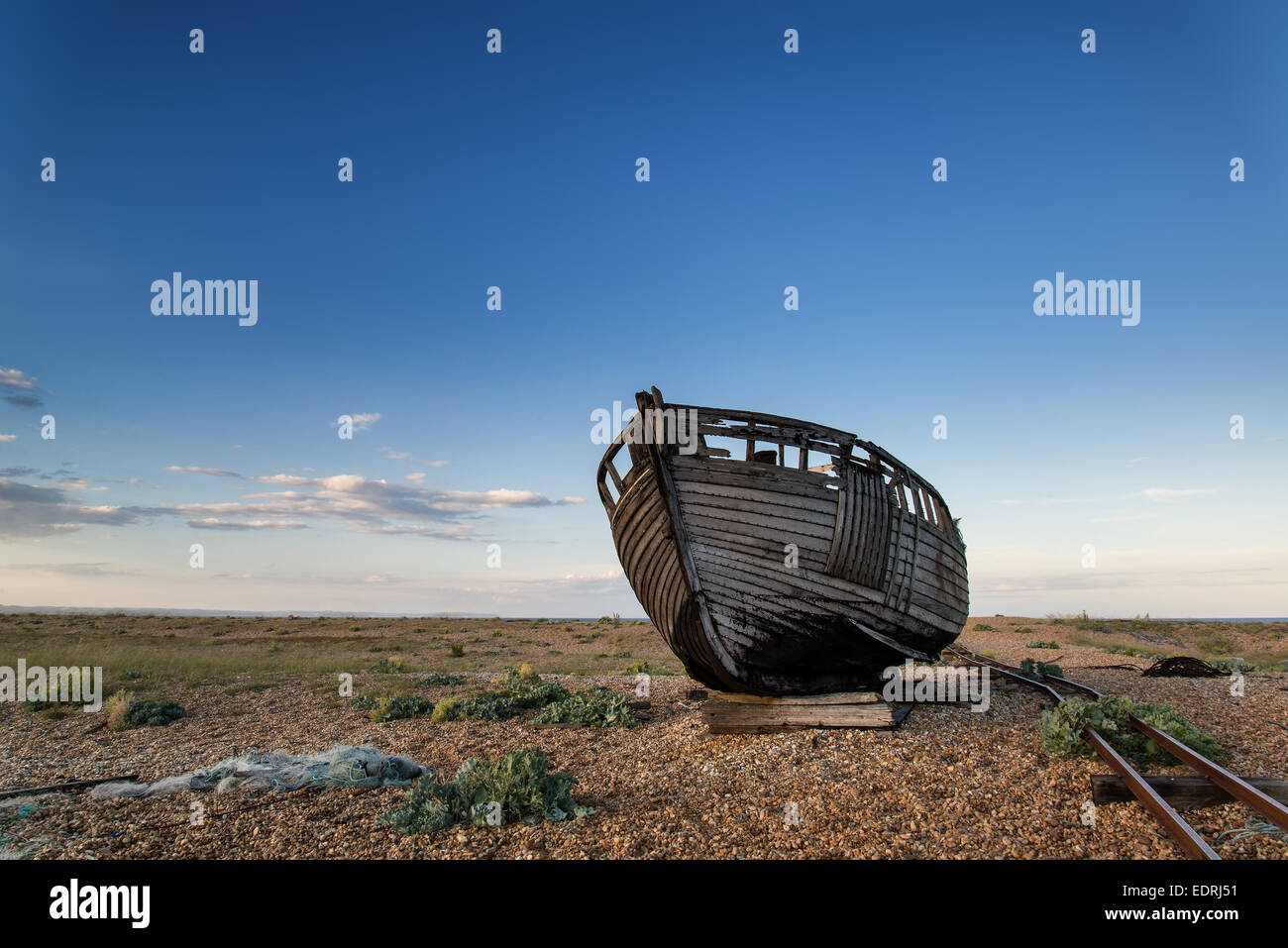 Abandoned fishing boat on shingle beach landscape at sunset Stock Photo ...