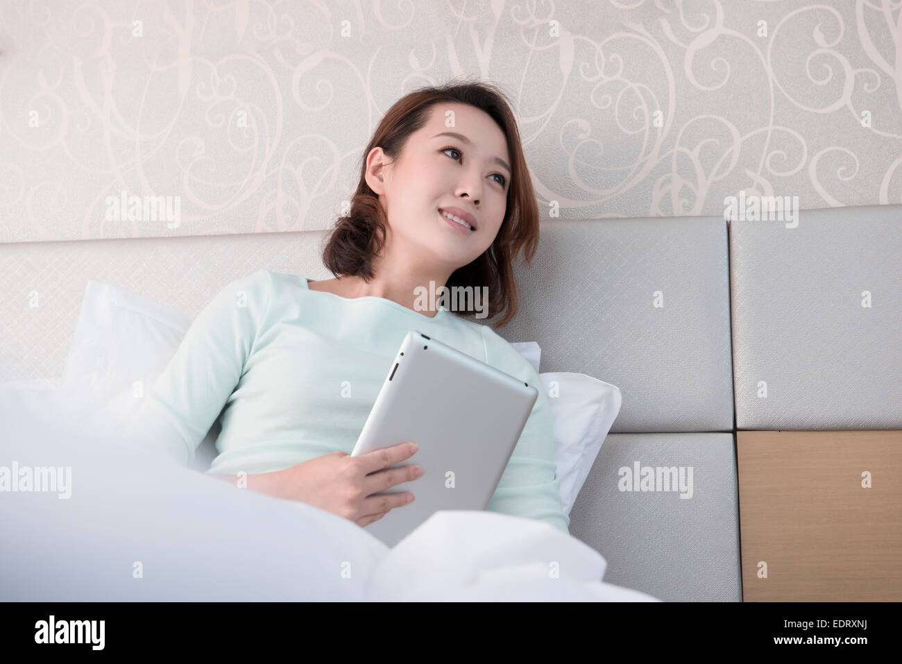 Young woman using digital tablet in bed Stock Photo