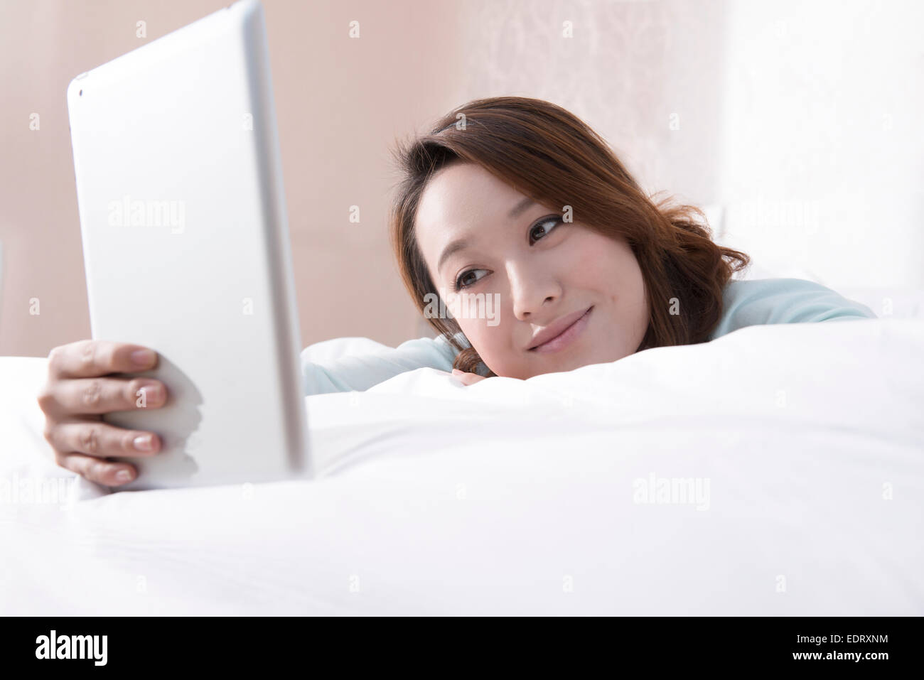 Young woman using digital tablet in bed Stock Photo