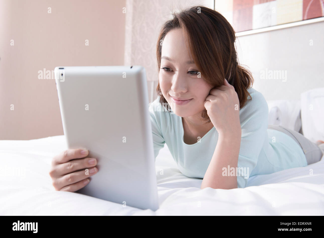 Young woman using digital tablet in bed Stock Photo