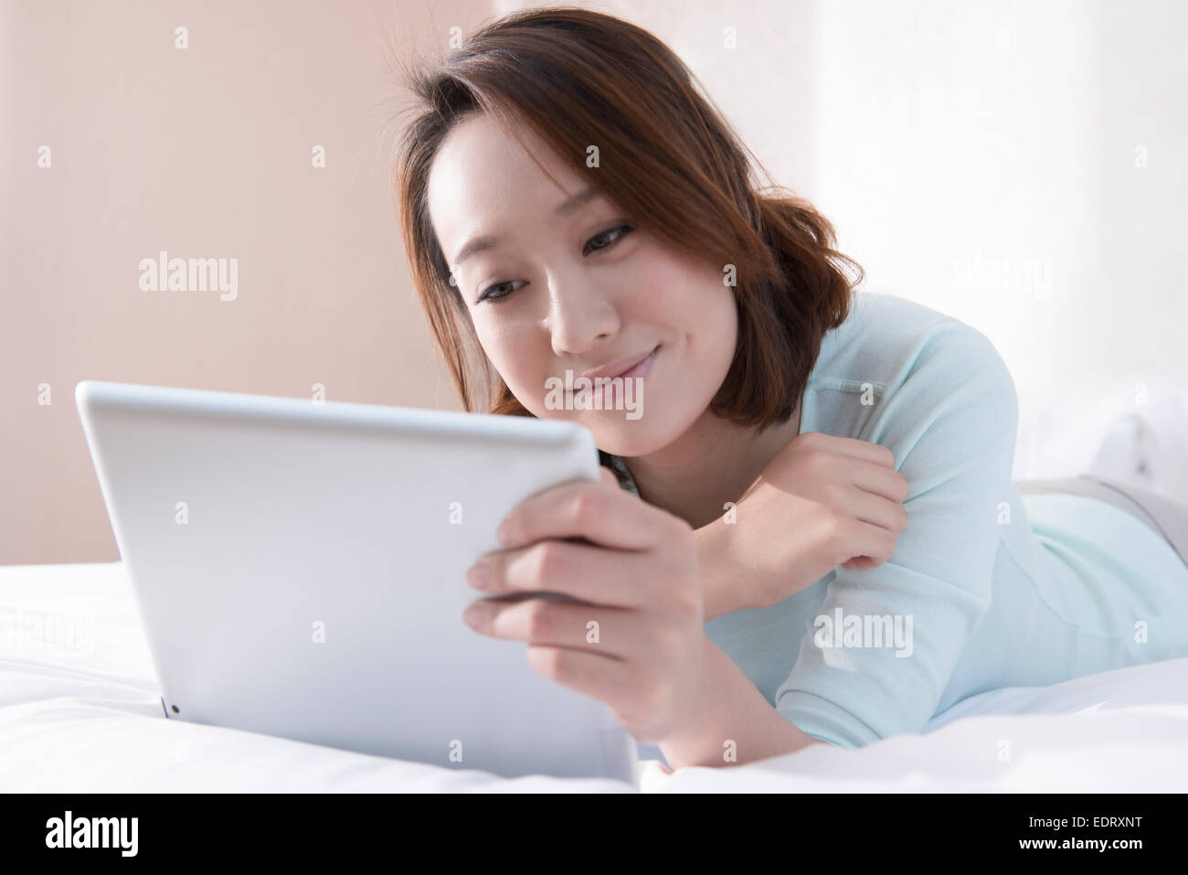 Young woman using digital tablet in bed Stock Photo