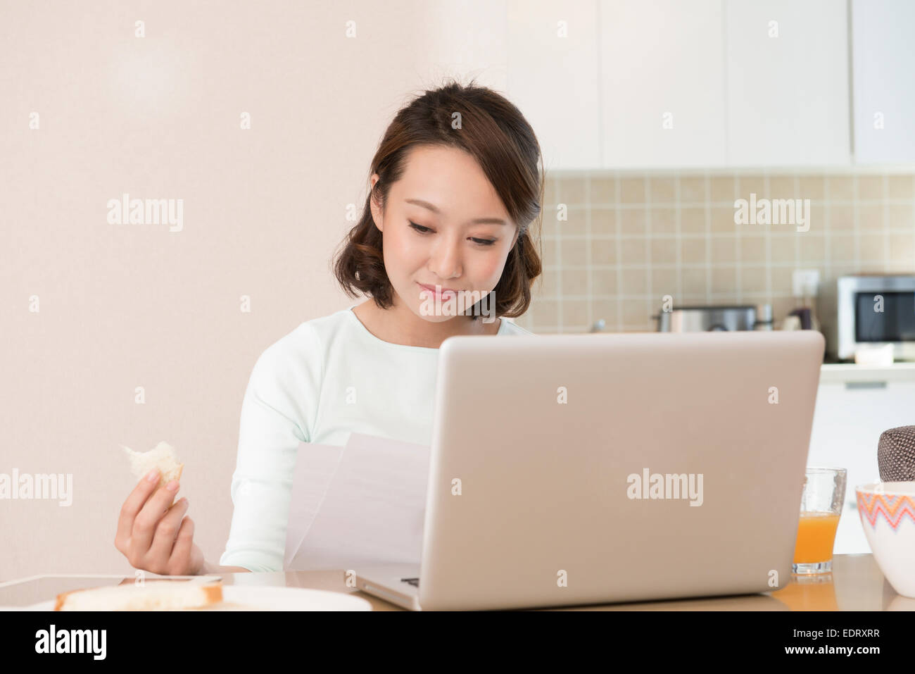 Young woman using laptop at breakfast Stock Photo
