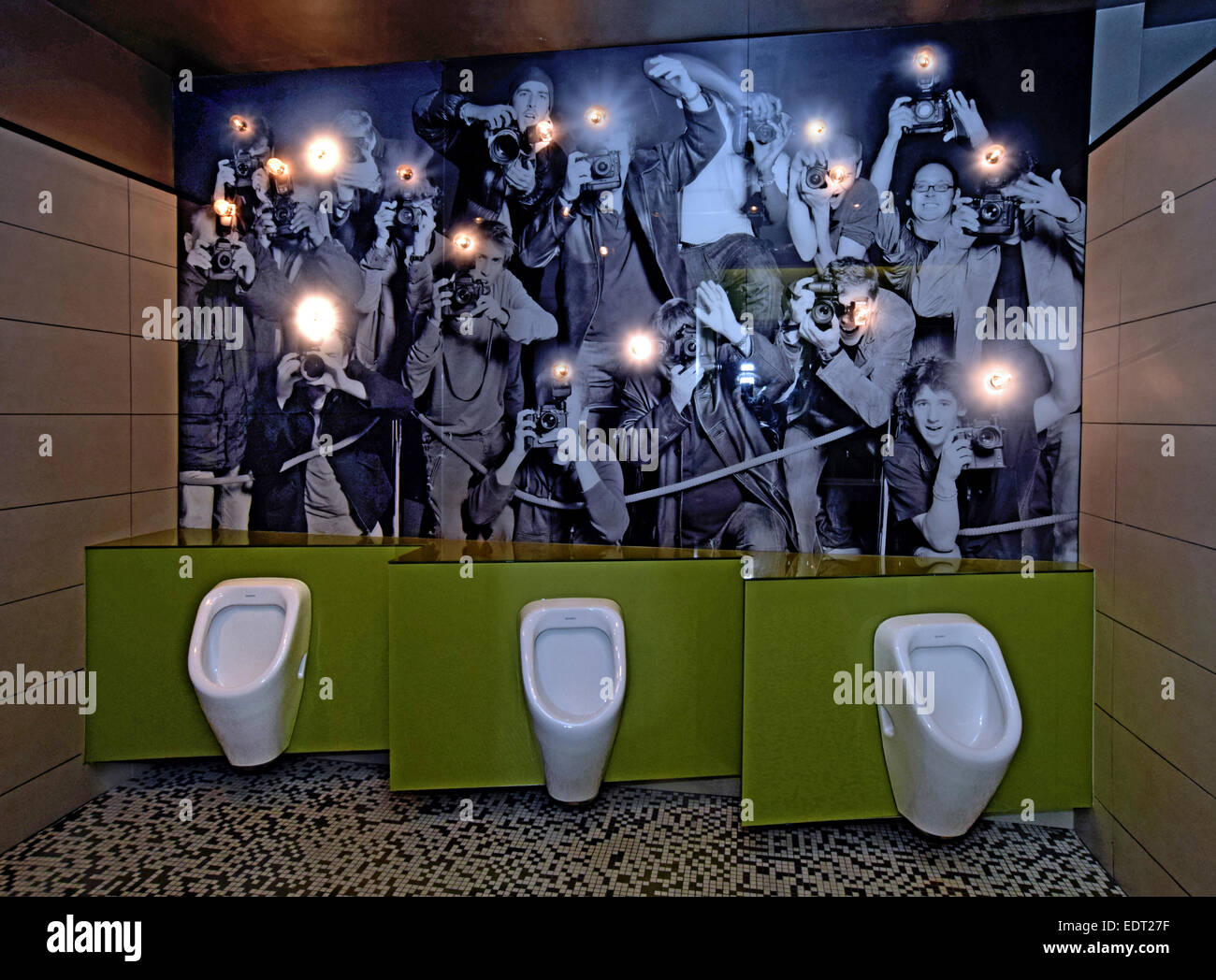 An ornate men's bathroom in an upscale restaurant in Long Island with a photo mural of paparazzi and flashing light bulbs. Stock Photo