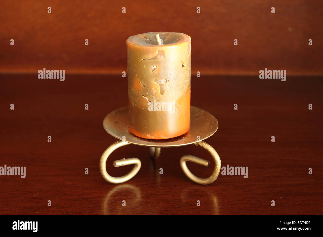 Artistic candle on a gold candleholder over a brown background Stock Photo