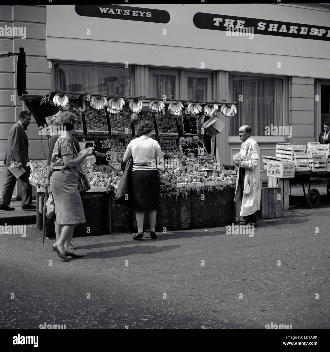 1960s, historical, female customers buying from a fruit stall outside The Shakespeare pub of the Watneys brewery, London. Stock Photo