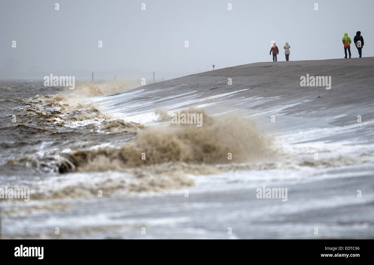 Spaziergänger laufen am 09.01.2015 auf dem Deich in Norddeich (Niedersachsen), an den die Wellen schlagen. Gleich zwei Orkanausläufer werden am Wochenende den Norden streifen. Foto: Matthias Balk/dpa +++(c) dpa - Bildfunk+++ Stock Photo