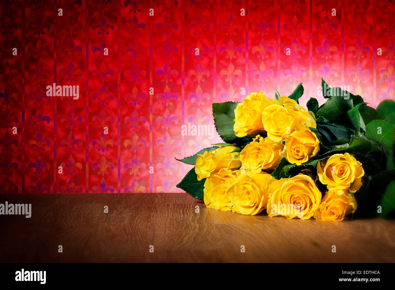 Bunch of yellow roses on a table and with red wellpaper, free space Stock Photo