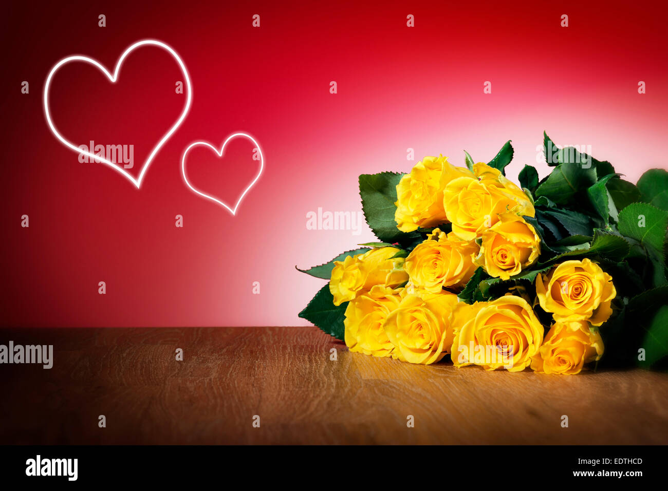 Bunch of yellow roses on a table and with red background and hearts Stock Photo