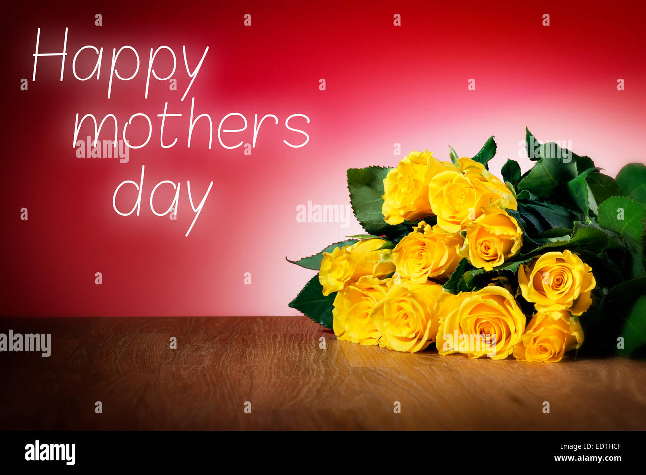 Bunch of yellow roses on a table and with red background, message happy mothers day Stock Photo