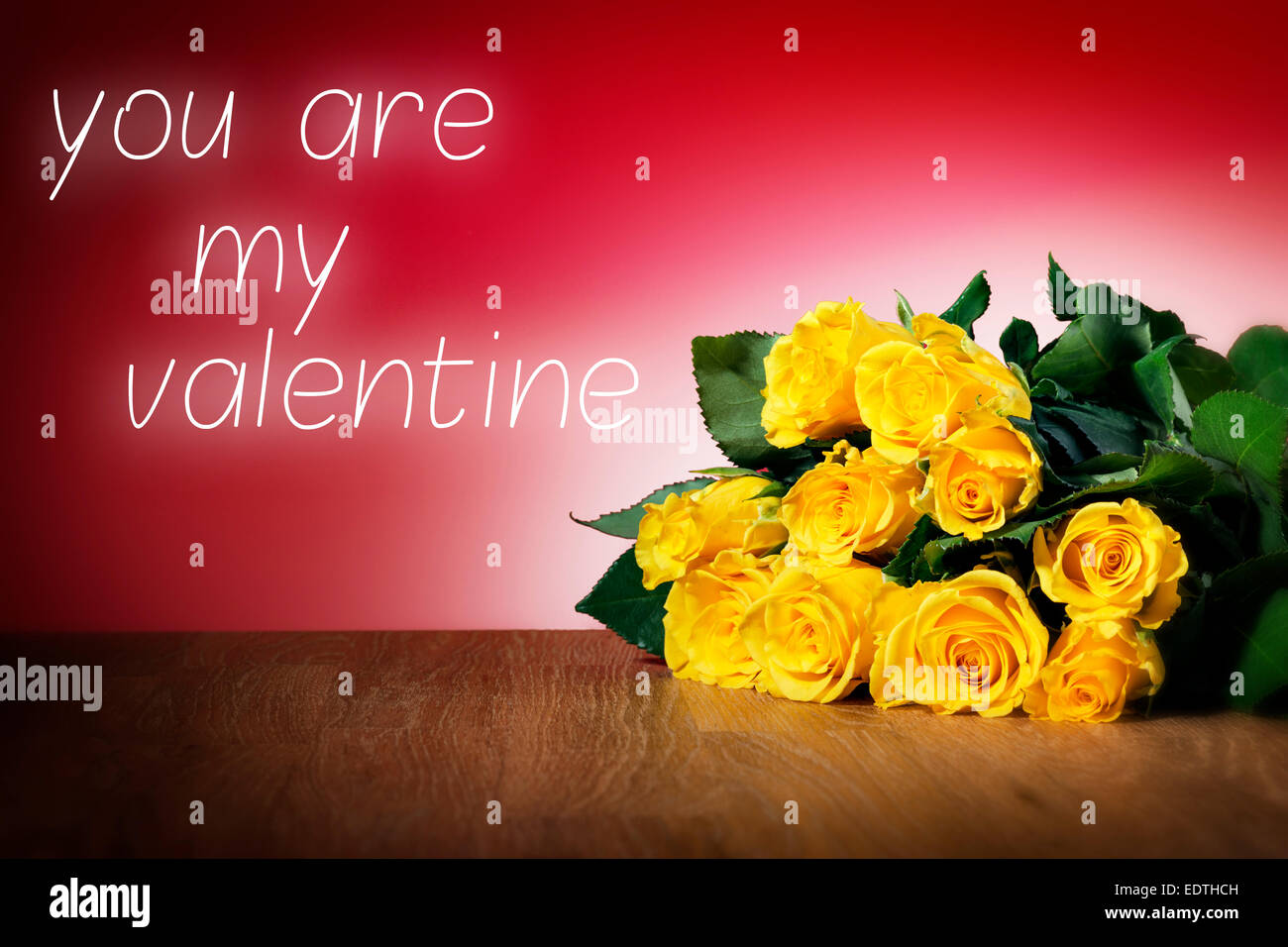 Bunch of yellow roses on a table and with red background and message you are my valentine Stock Photo