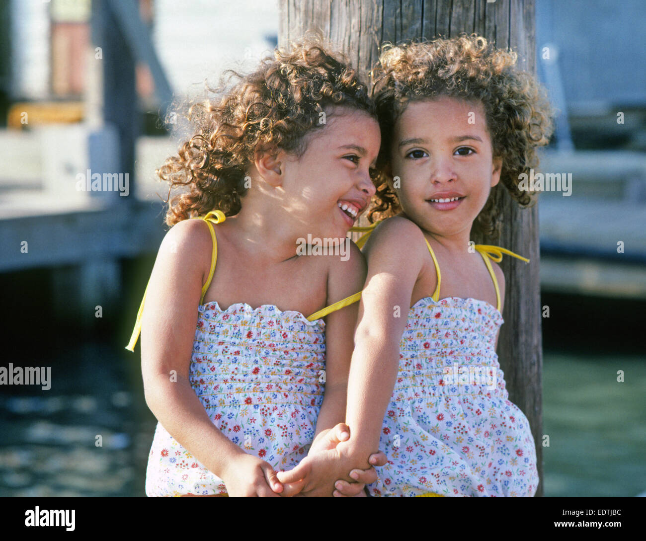 Two young black identical twins sitting on a dock on Padre island, Texas  Stock Photo - Alamy