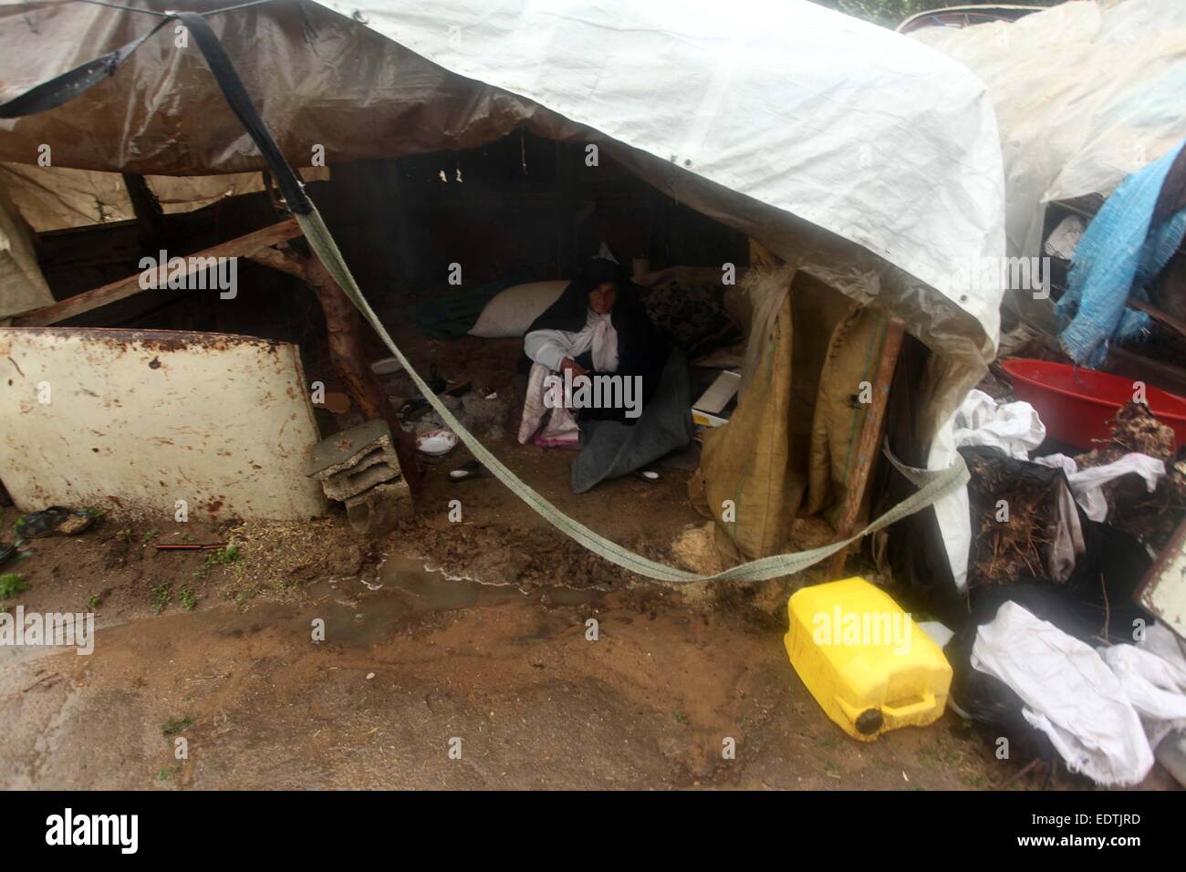 A Palestinian woman sits in a tent near the rubbles of her house ...