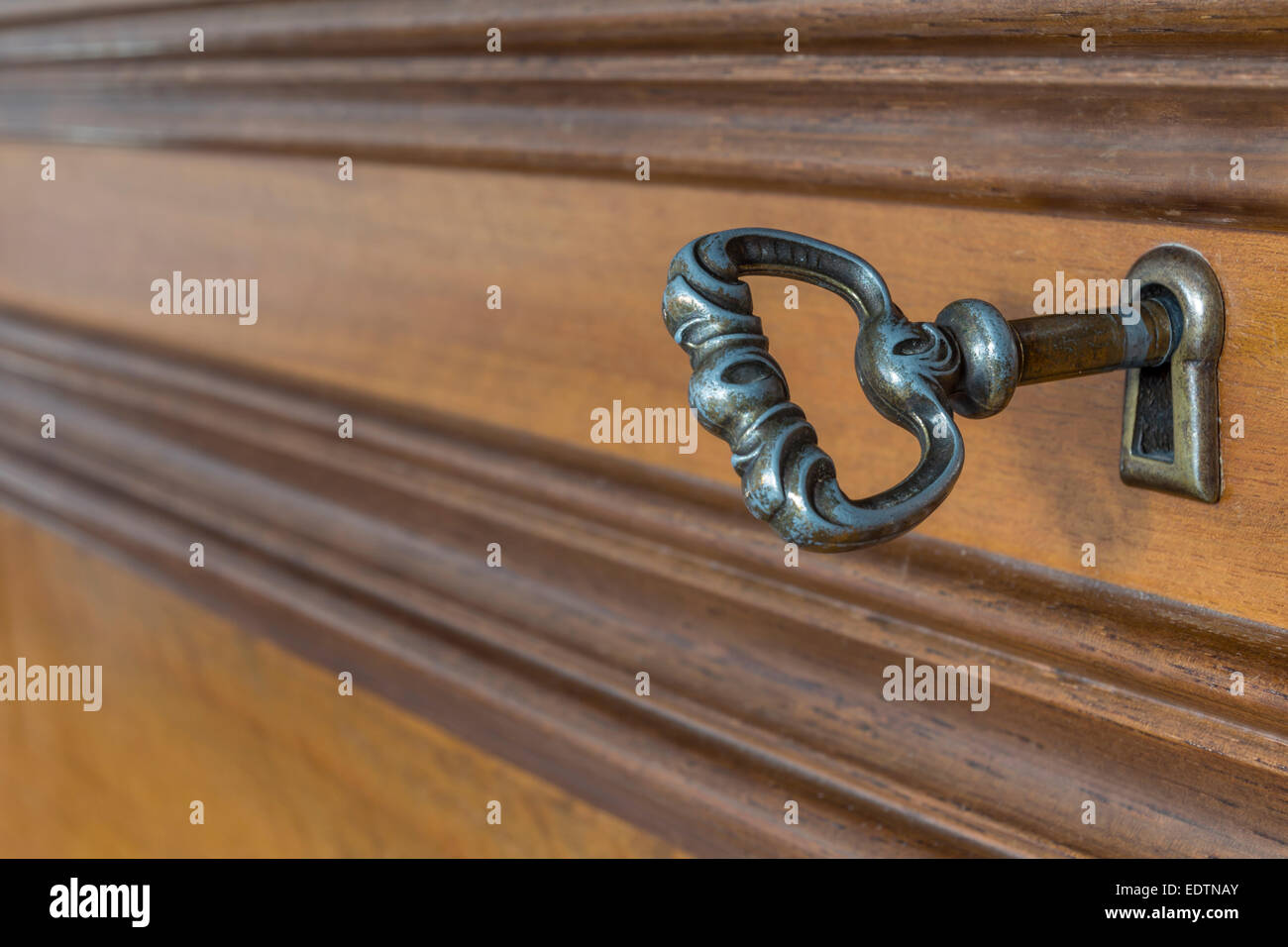 Ancient key in the keyhole of antique furniture Stock Photo