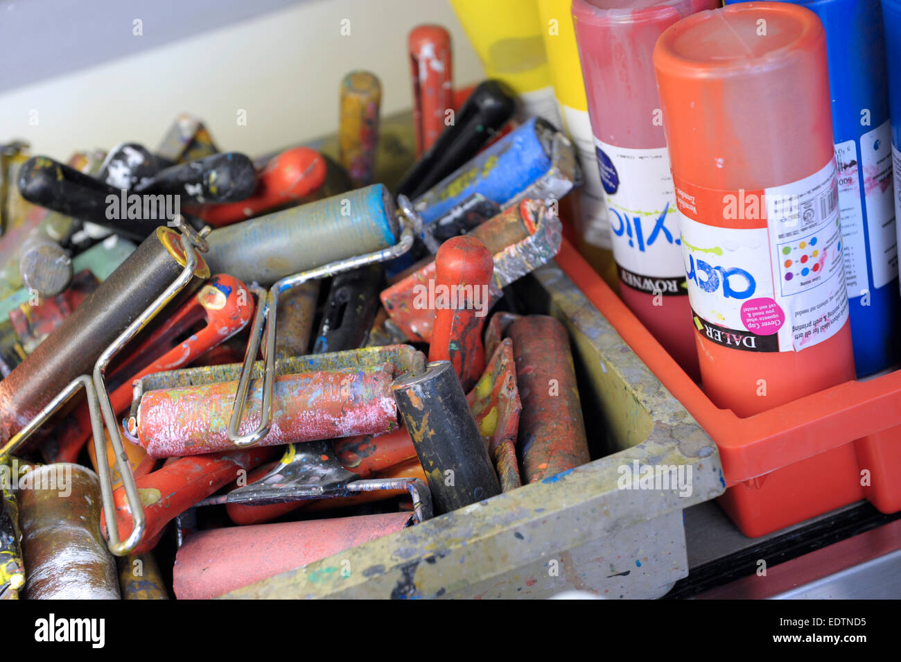 Silk screen rollers and acrylic paint pots in a school art room Stock