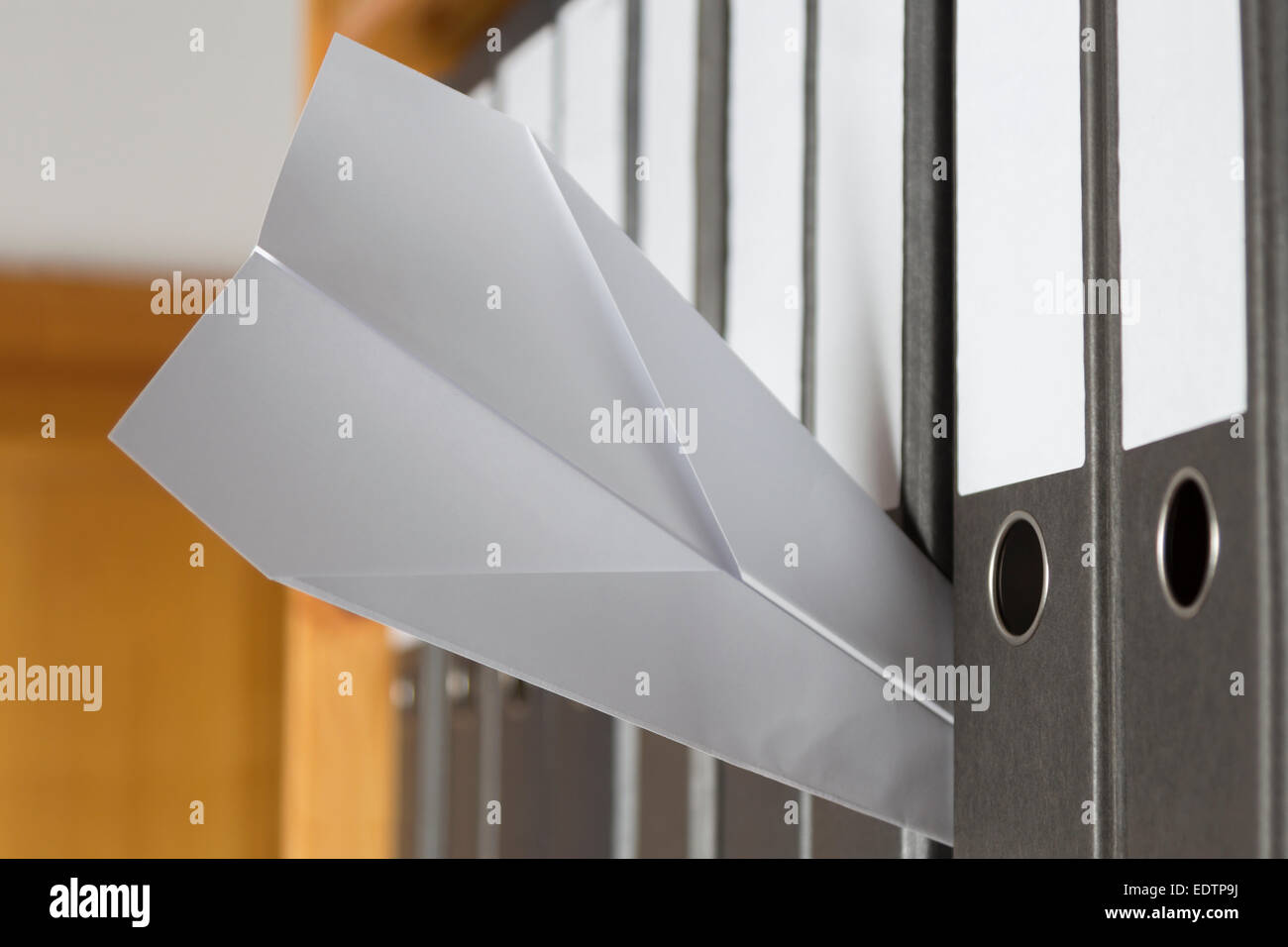 Paper Plane stuck between folders on a boring day in the office Stock