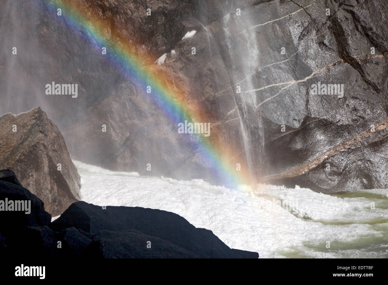 Rock face, rainbow, and frazil ice at the base of Lower Yosemite Falls in Yosemite National Park Stock Photo