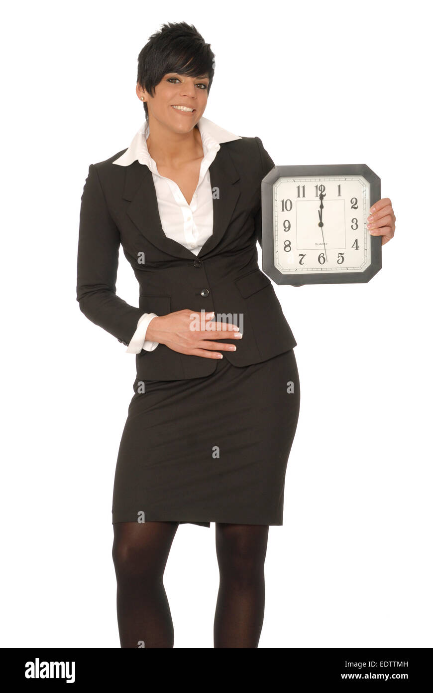 Business woman holding a clock that reads 12 o'clock, and gesturing to her stomach.  Can represent lunchtime hunger. Stock Photo