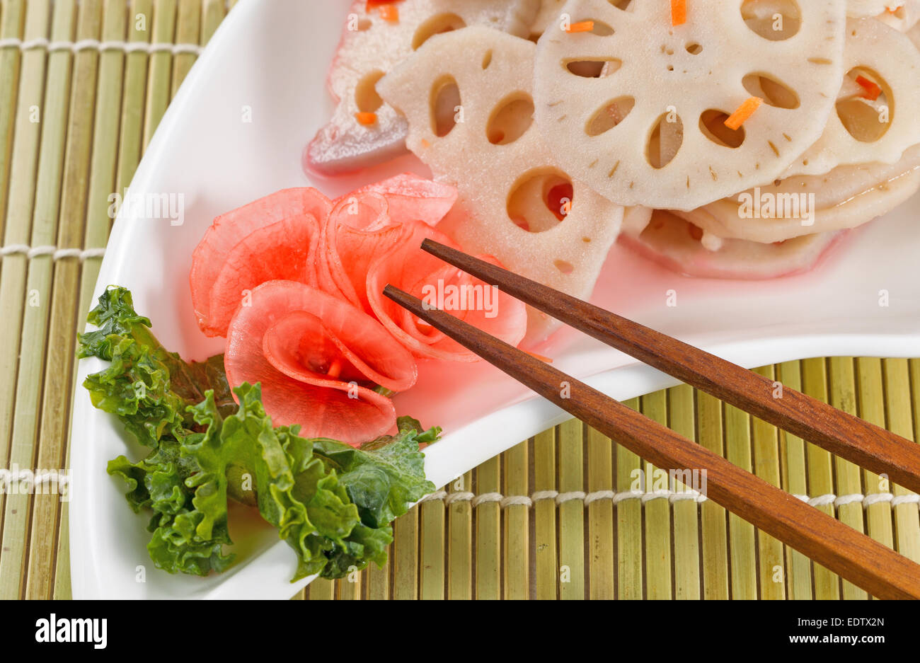 Chinese radish, in white dish, with chopsticks on natural bamboo place mat Stock Photo
