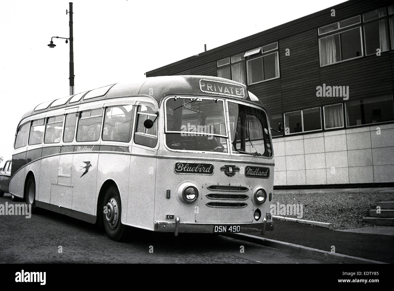 1960s historical picture showing a Midland Bluebird coach on private hire parked outside a modern housing block awaiting its passengers, Scotland, UK. Stock Photo