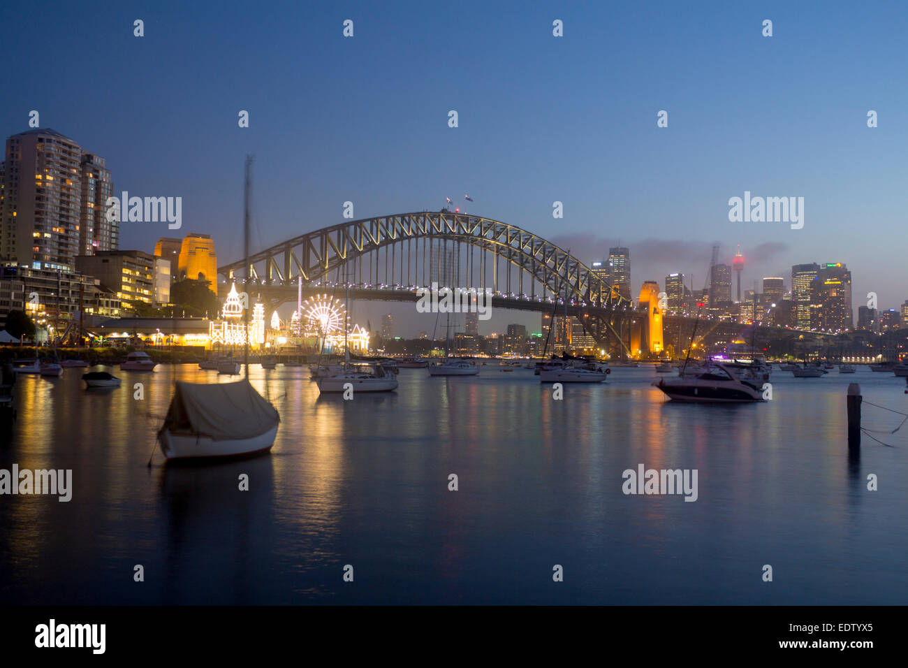 Lavender Bay boats in harbour view to Sydney Harbour Bridge CBD skyline skyscrapers and Luna Park at night Sydney NSW Australia Stock Photo