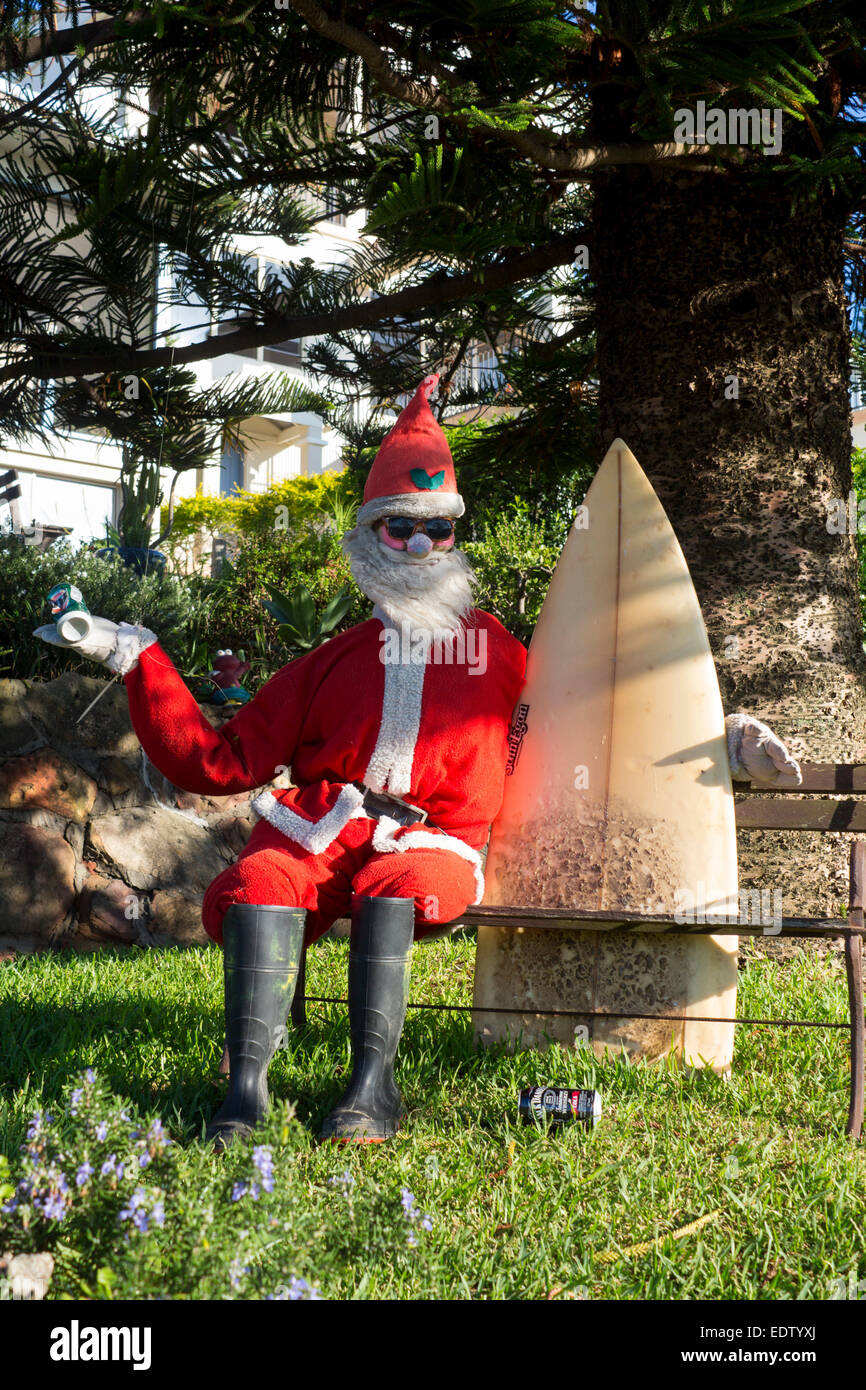 Surfer Santa Claus Surfing Surfie Santa Claus model sitting on garden bench holding surfboard holding can of beer NSW Australia Stock Photo