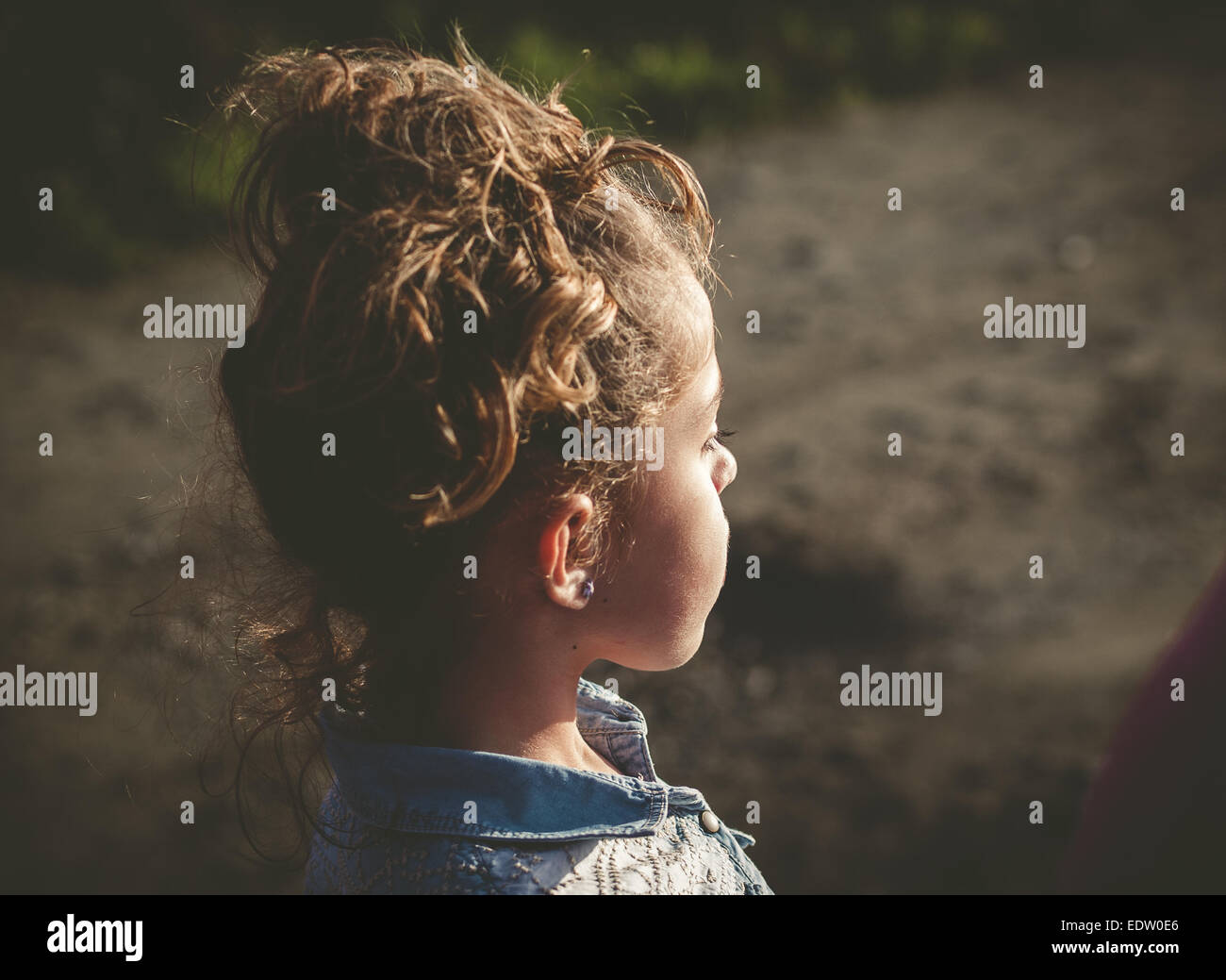 Little girl lookin aside outdoors in a sunny day Stock Photo