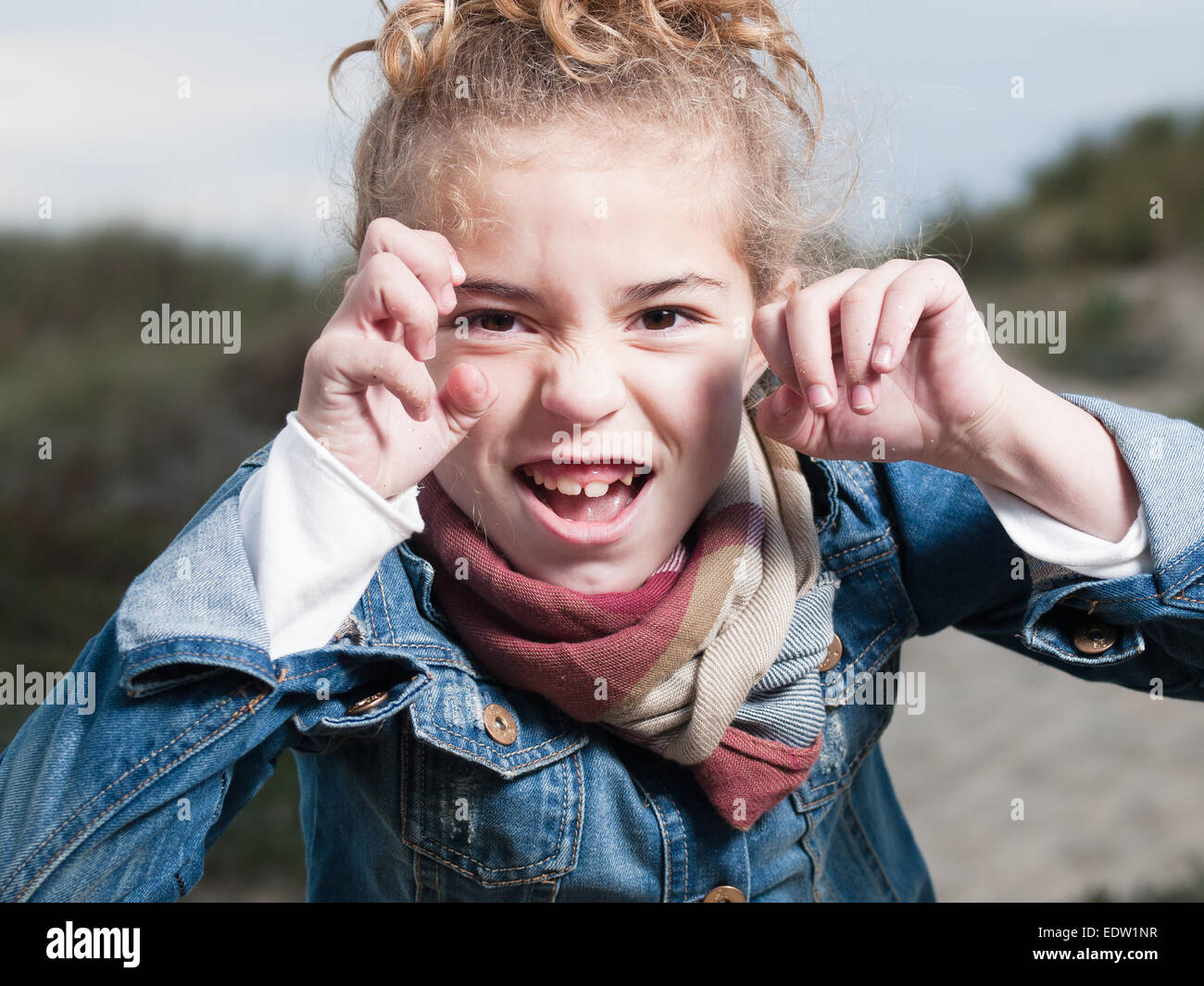 Blonde girl putting a frightening face outdoors Stock Photo