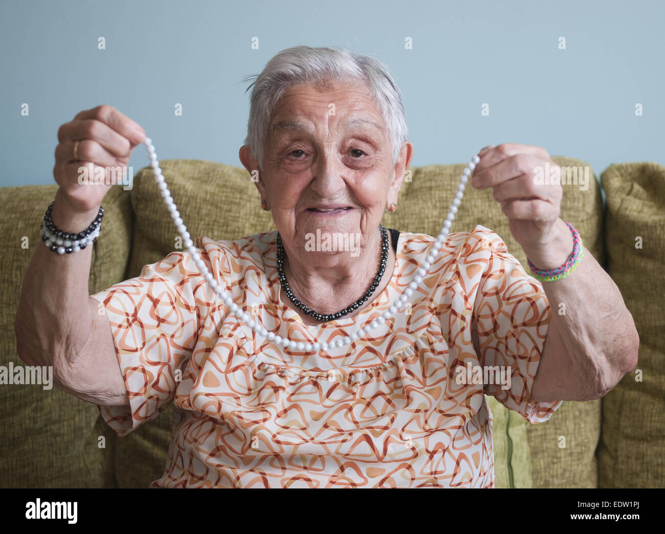 Elderly woman showing a necklace which she has made Stock Photo