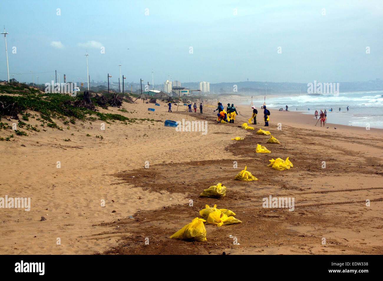 Many unknown Municipal workers cleaning up debris on beach in Durban