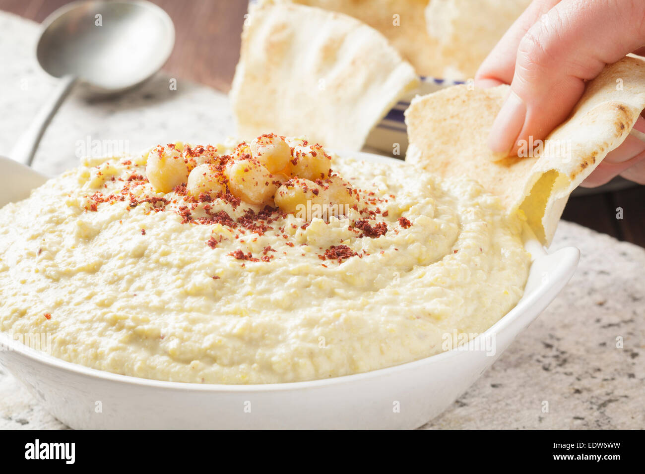 Hand dipping flat bread into hummus Stock Photo